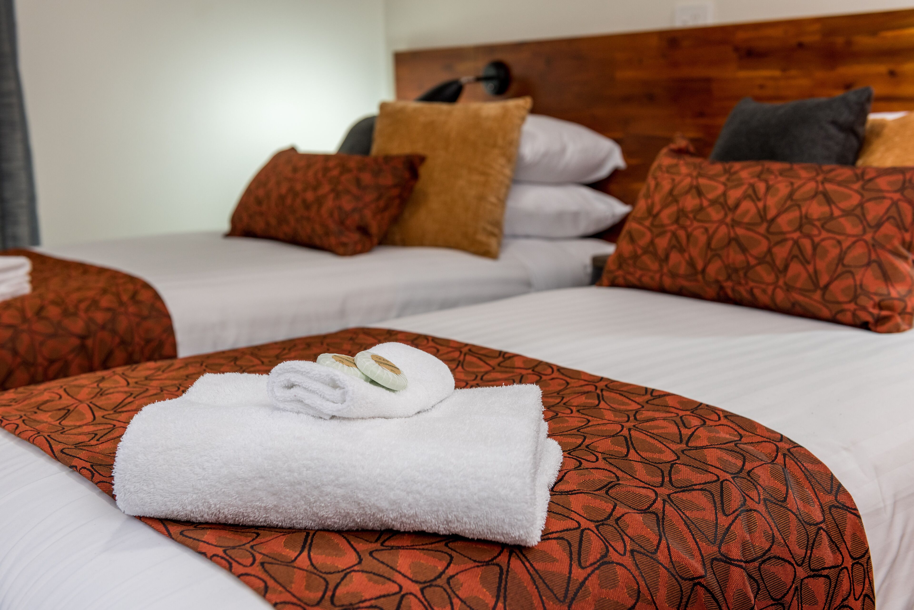 Una habitación de hotel con dos camas, cada una con ropa de cama y almohadas estampadas.
