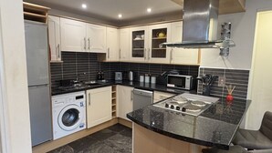 Een kleine keuken met een wasmachine, magnetron en gasfornuis.