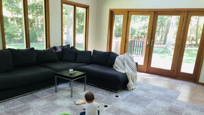 En stue med en hjørnesofa, et sofabord og en legetæppe.