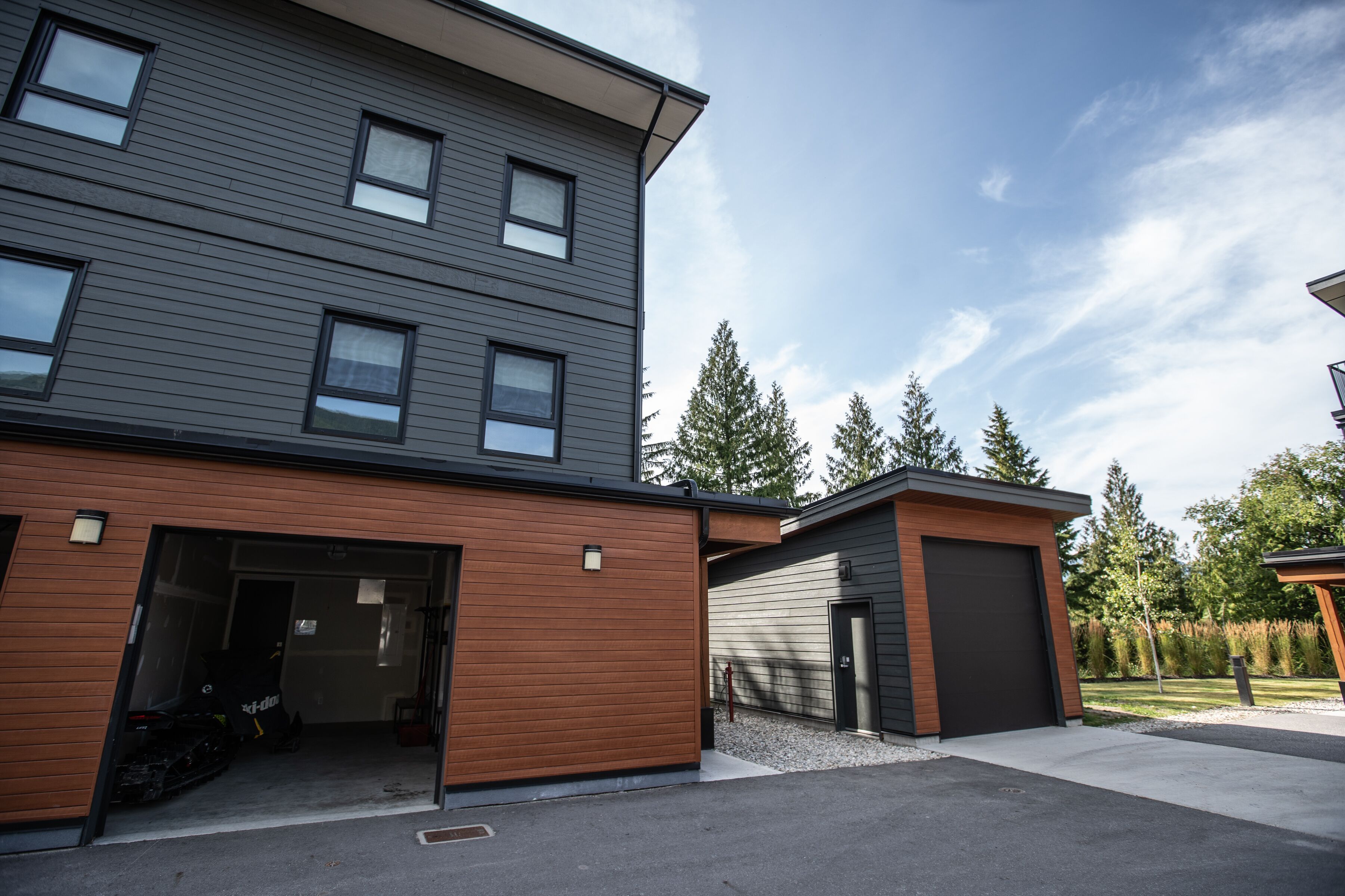 A modern multi-story building with a garage and a covered outdoor area.