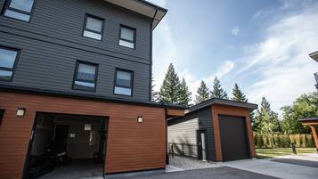 A modern multi-story building with a garage and a covered outdoor area.