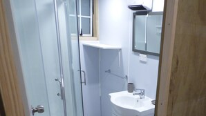 Een badkamer met een douchecabine van glas, een wastafel en een toilet.
