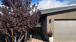 A modern building with a garage, a paved driveway, and a tree with dark leaves.