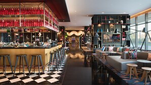 Een bar met krukken, een geruit vloertje en planken vol flessen.