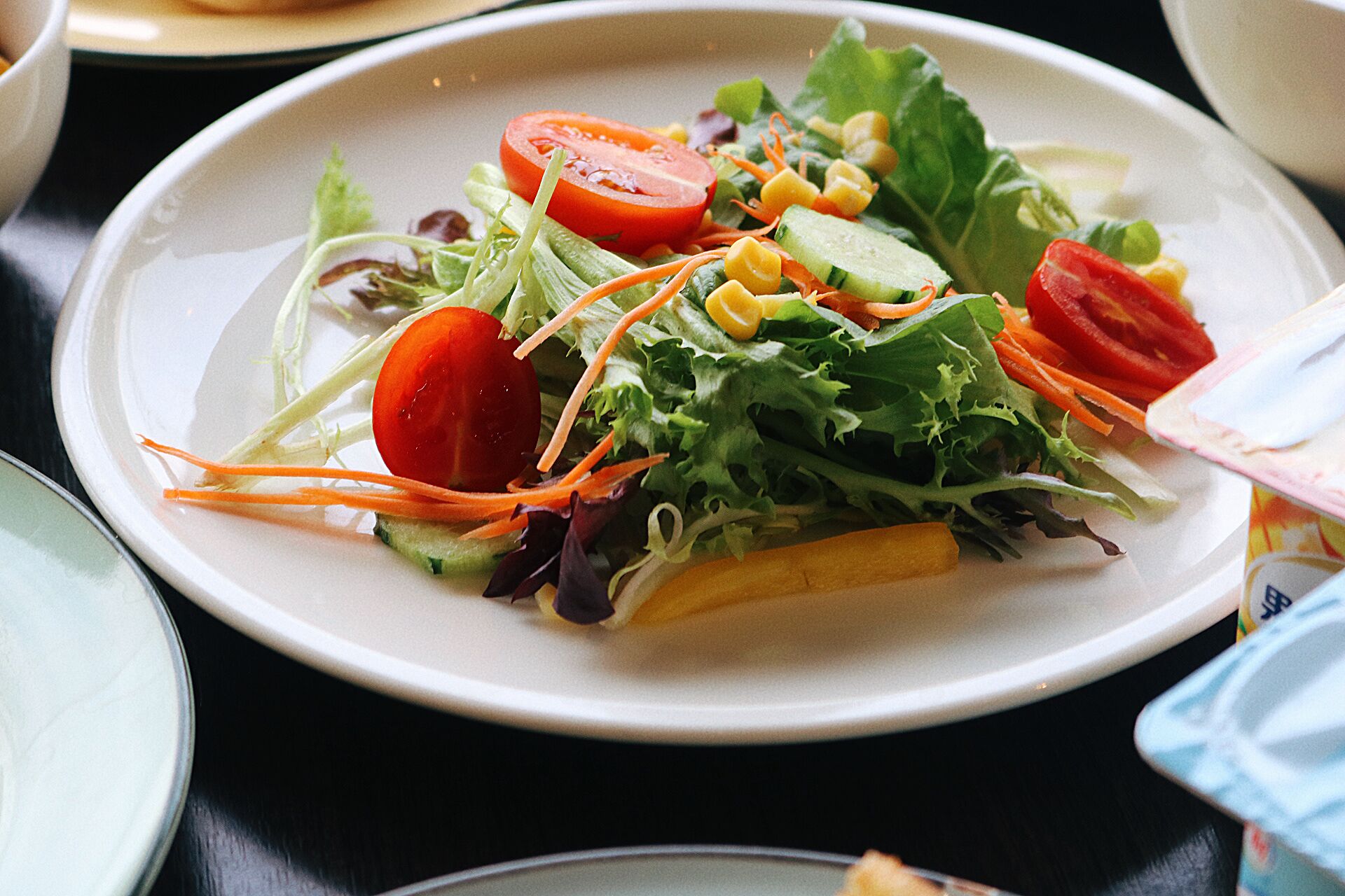 Ensalada de hojas verdes mezcladas con tomates, pepinos y zanahoria rallada.