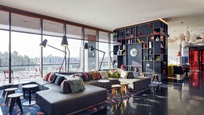 Een moderne woonkamer met een hoekbank, ronde tafels en een grote boekenkast.