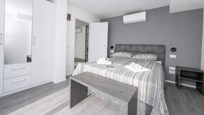 A bedroom with a bed, bedside tables, a bench, a wardrobe, and an air conditioning unit. - Rustichel fantastic Lake View, Toscolano Maderno, Italy (Toscolano Maderno)