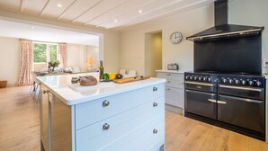 Una cocina moderna con una isla central, hornos dobles y un amplio ventanal con cortinas.