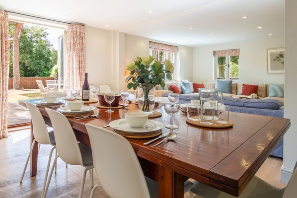 A dining area with a wooden table set for a meal, surrounded by chairs.