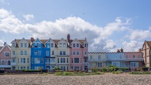 Una hilera de casas coloridas bajo un cielo despejado con algunas nubes.