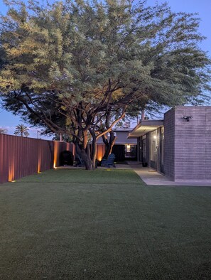 A backyard with a tree, a barbecue grill, and a building with a brick exterior. - 2BR Pet-Friendly Condo, Walkable Location (Phoenix)