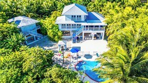 Une grande maison avec une piscine, entourée d’une végétation luxuriante.