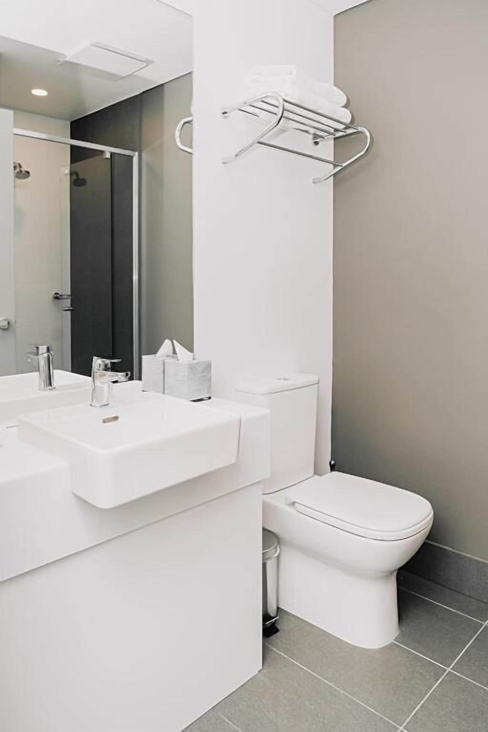 A modern bathroom with a white sink, a toilet, and a shower area.