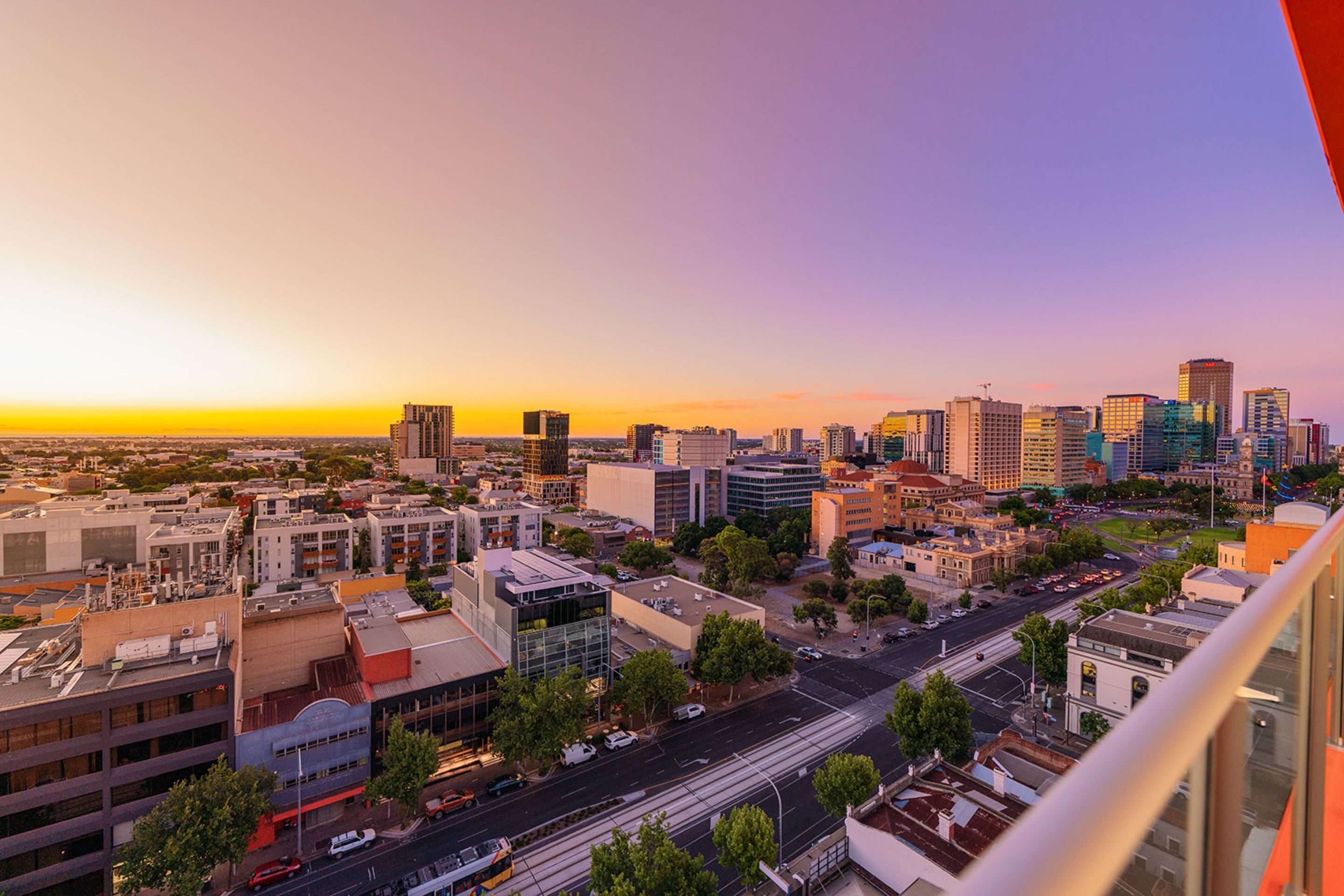 A cityscape at sunset with modern buildings, a clear sky, and a view of the urban landscape.