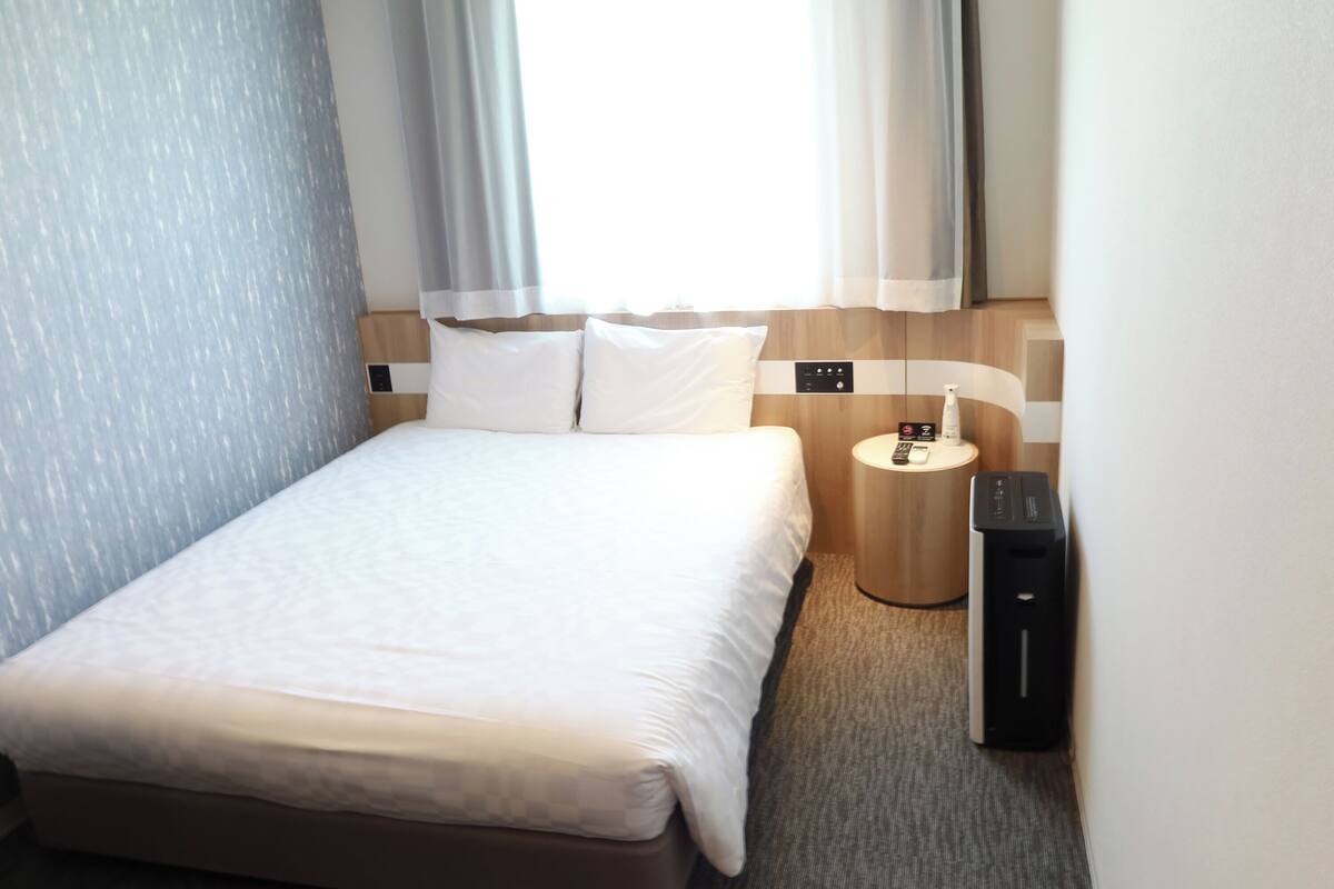 A neatly made bed with white linens in a hotel room.
