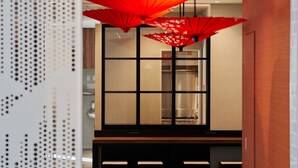 Un interior moderno con una zona de bar, muebles de madera y sombrillas rojas.