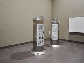 Two trash cans with instructions in Japanese, placed on a grey floor against a textured wall.