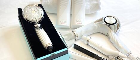 A set of hair care tools including a hair clipper, a hairdryer, and bottles of shampoo and treatment, arranged on a bed.