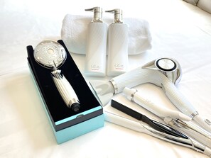 Un conjunto de herramientas para el cuidado del cabello, incluyendo una máquina de cortar, un secador y botellas de champú y tratamiento, sobre una cama.