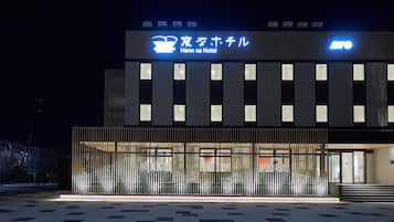 The exterior of Henn na Hotel with a modern design, featuring a prominent sign and a gated entrance.