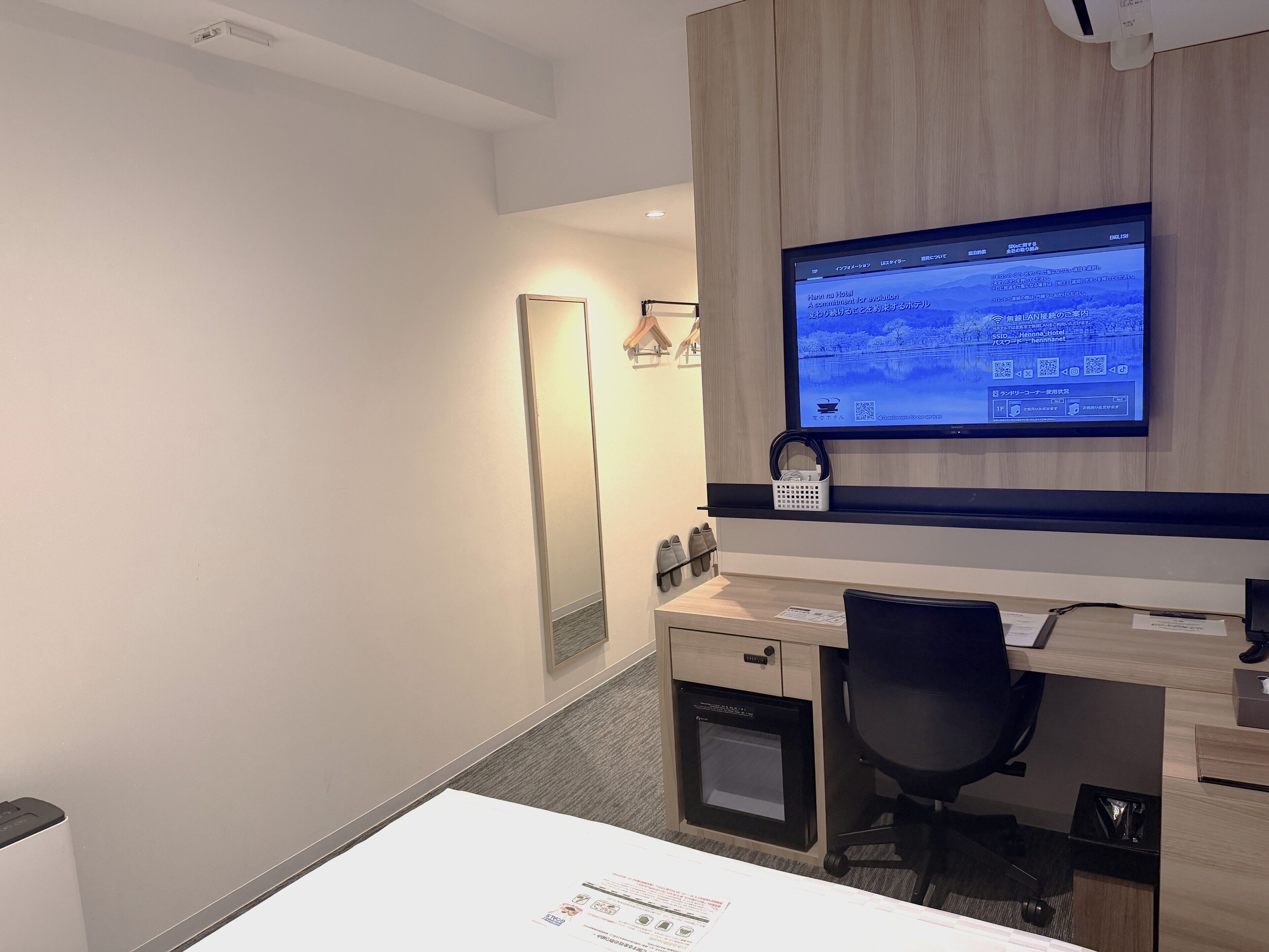Ein Hotelzimmer mit Schreibtisch, Stuhl und einem Wand-Fernseher.