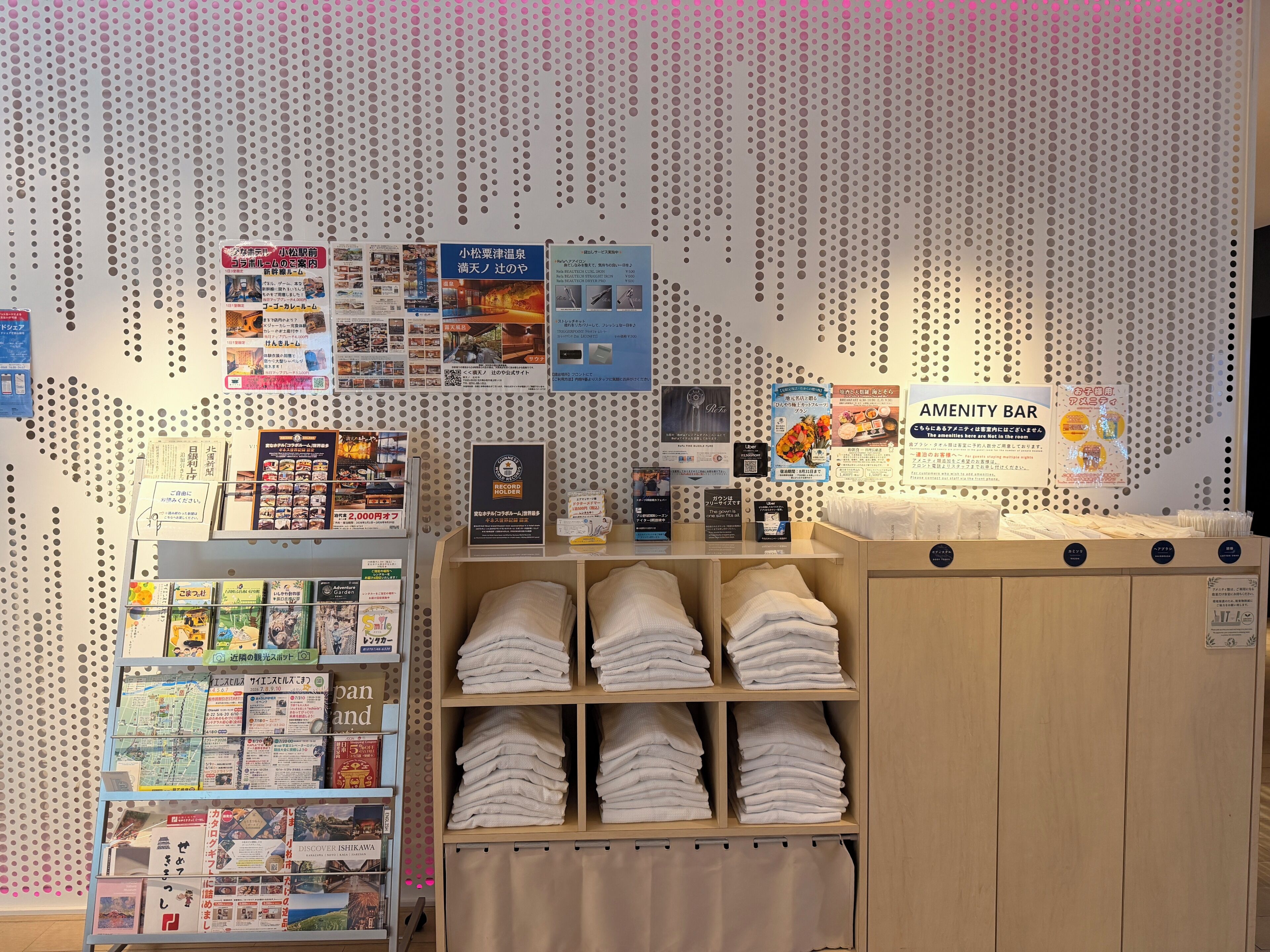 A hotel reception area with a bulletin board, informational pamphlets, and neatly folded towels.