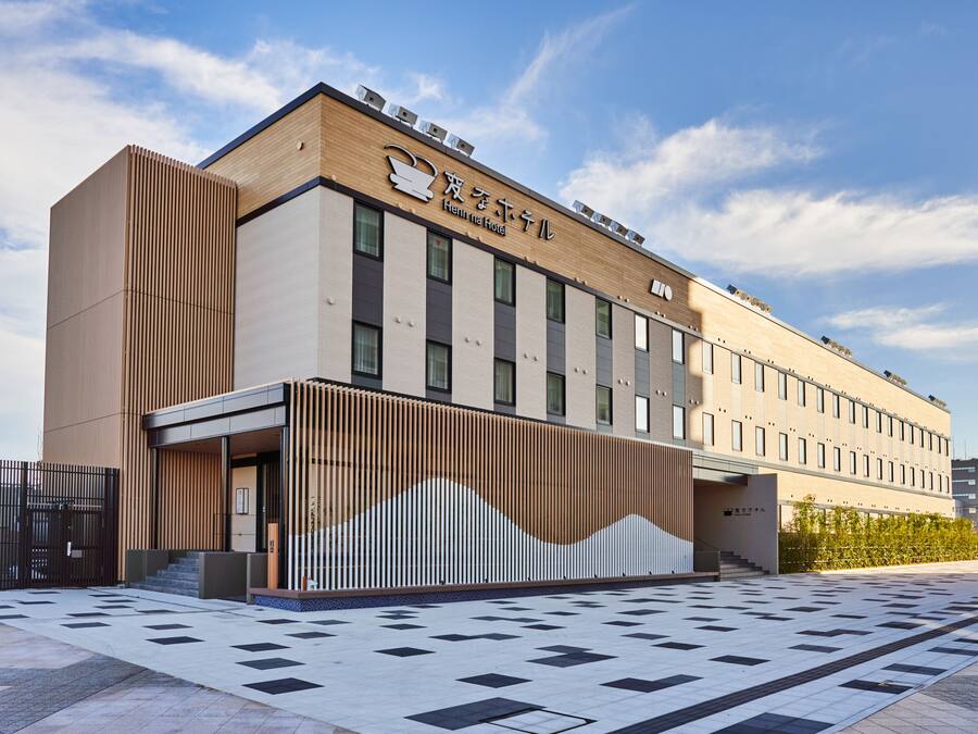 Un hotel moderno con techo plano, ventanas amplias y un área de entrada con pavimento estampado.