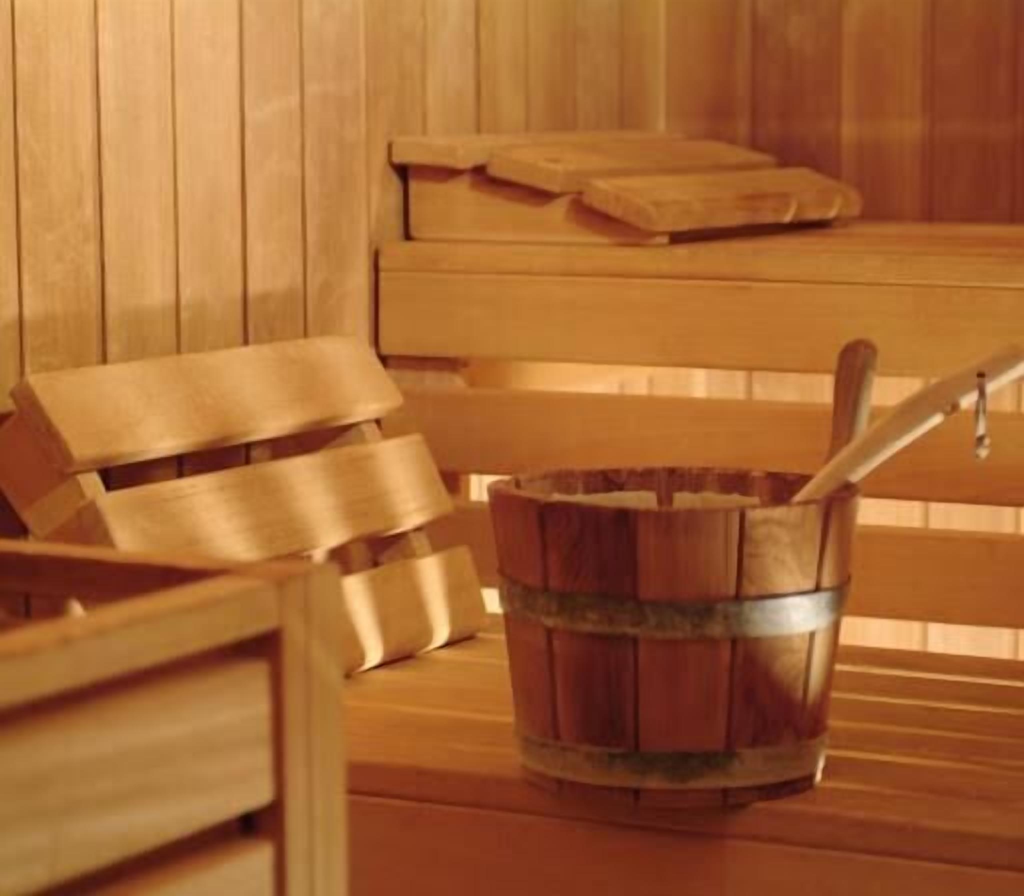 Una sauna de madera con bancos y un balde.