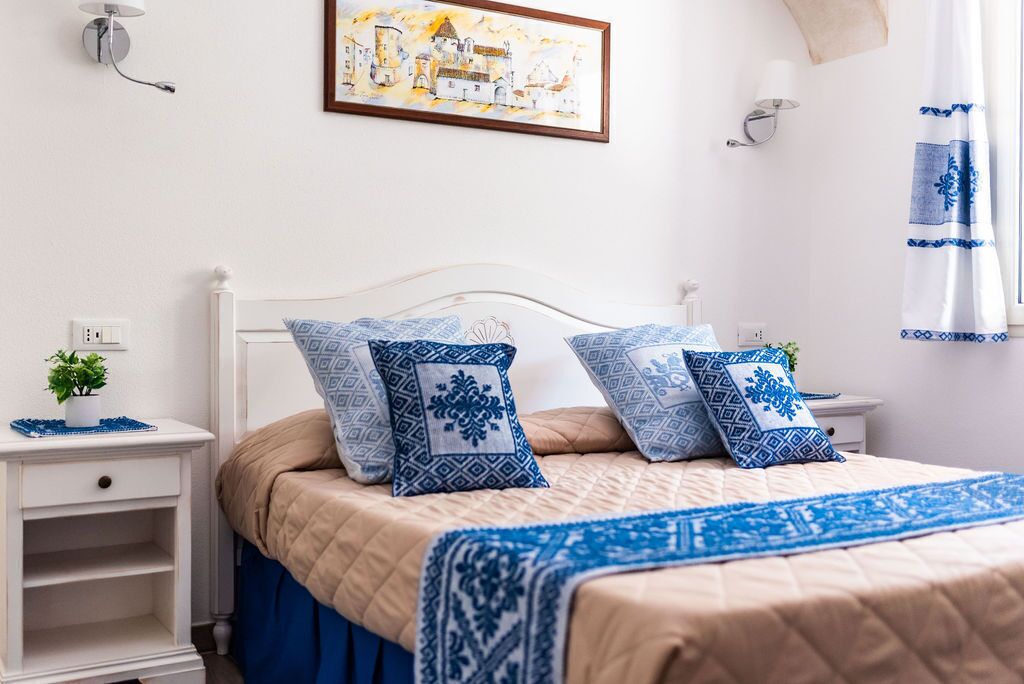 Une chambre à coucher bien rangée, avec un lit, des tables de chevet et une lampe fixée au mur.