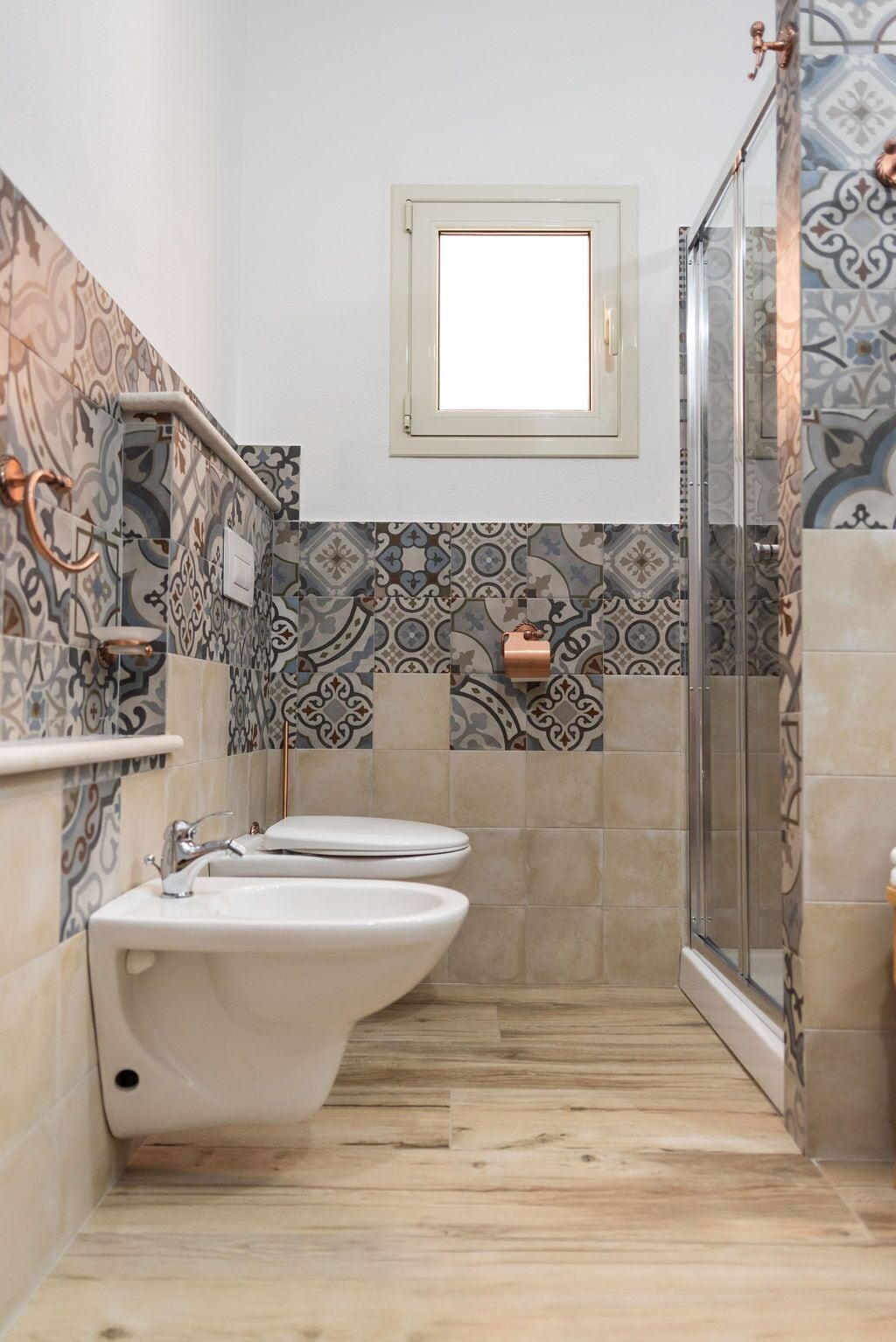 A bathroom with two toilets, a sink, a shower, and a window.