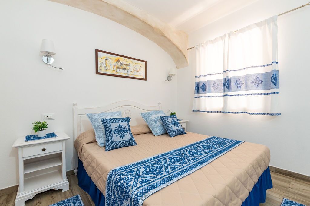Une chambre à coucher avec un lit, des tables de chevet, un tableau et une fenêtre avec des rideaux.