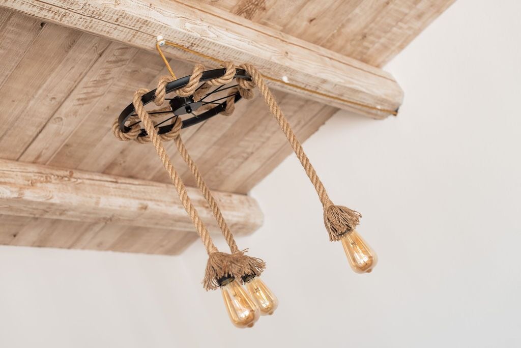 A rustic wooden ceiling with exposed beams and two hanging light fixtures with tassels.