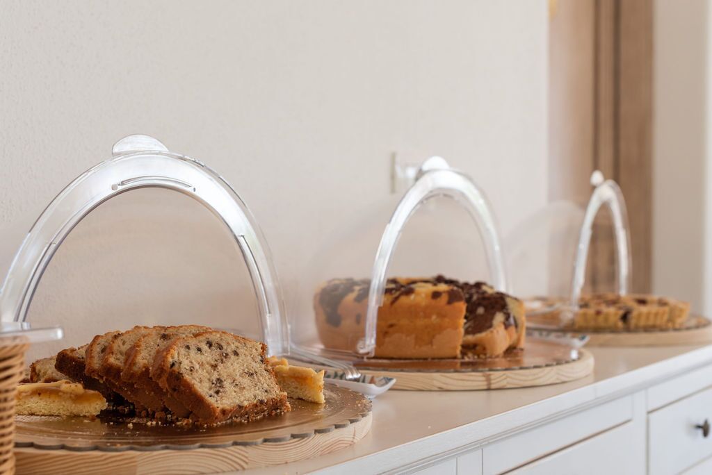 Una exhibición de varios productos de repostería bajo campanas de cristal en una barra.