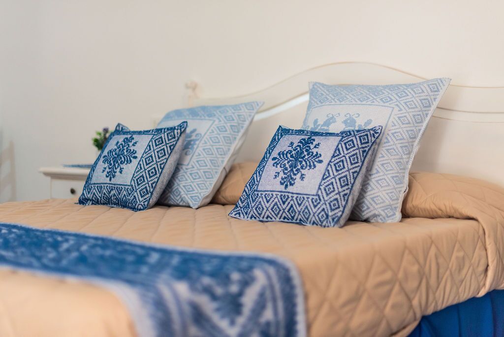 Una cama con colcha color beige y almohadas con estampado azul.