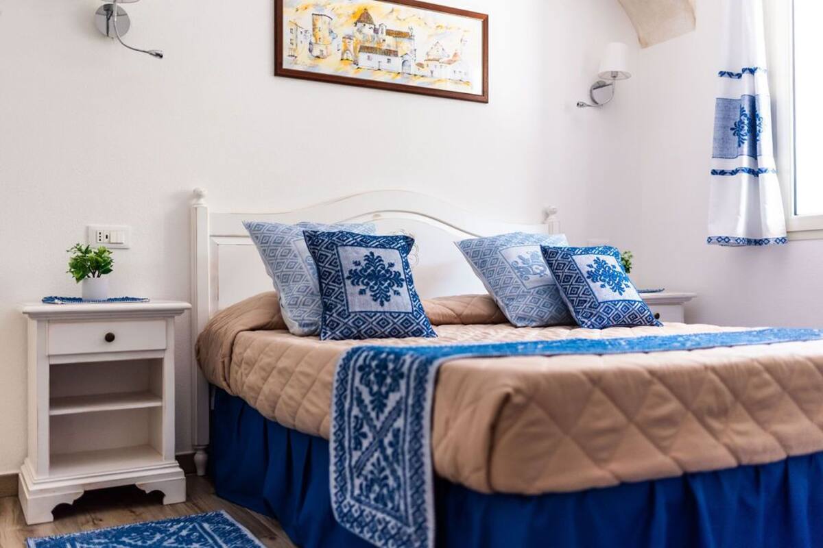 A neatly arranged bedroom with a bed, nightstand, and a wall-mounted lamp.