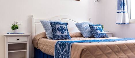 Un dormitorio ordenado con cama, mesita de noche y lámpara de pared.
