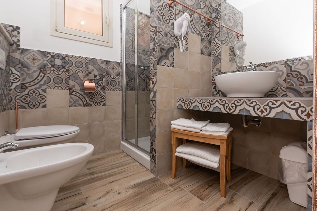 Een badkamer met een douche, twee toiletten, een wastafel en een wastafelmeubel met een spiegel.