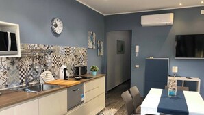 Eine moderne Küche mit Mikrowelle, Toaster und Spüle. Ein Essbereich mit Tisch und Stühlen ist ebenfalls vorhanden.