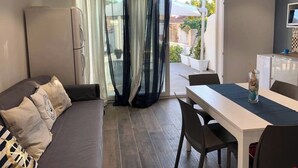 Ein modernes Wohnzimmer mit einer Couch, einem Esstisch und einem Kühlschrank.