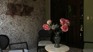 Un muro de piedra, una puerta de madera y una mesa con un jarrón de flores.