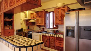 Una cocina con armarios de madera, un refrigerador de acero inoxidable y una encimera con azulejos.
