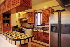 A kitchen with wooden cabinets, a stainless steel refrigerator, and a tiled countertop.