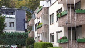Un edificio residencial de varios pisos con balcones, una escalera y un coche estacionado en la calle.