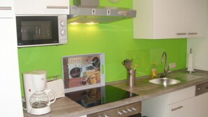 Una cocina con microondas, cafetera, lavabo y un cartel en la pared.