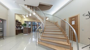 Een modern interieur met een gebogen trap, gepolijste tegelvloeren en een receptie met een balie en planken.