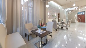 Een moderne hotellobby met een eetgedeelte, een trap en uitzicht naar buiten.