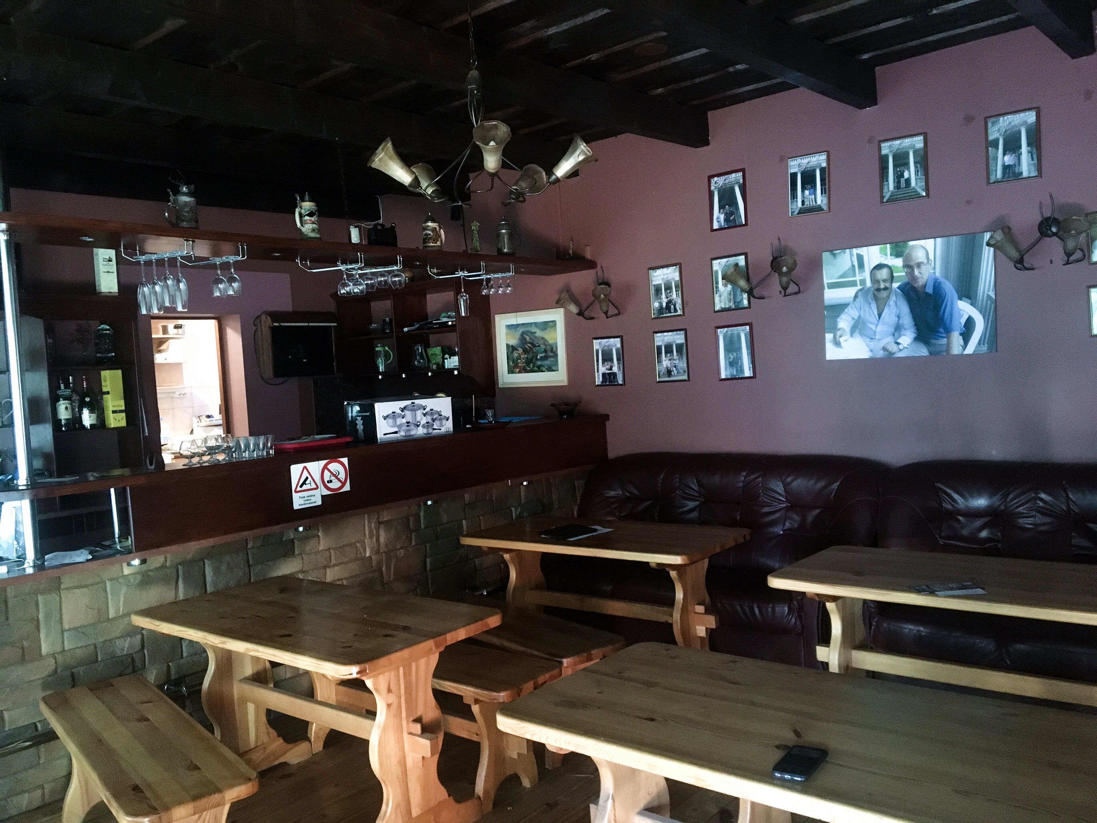 A cozy bar area with wooden tables and benches, a stone wall, and a leather couch.