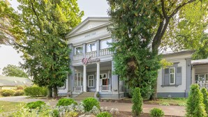 Een gebouw met twee verdiepingen, een veranda en zuilen, met de tekst 'Valensja Hotel'.