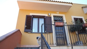 A yellow building with a staircase, a metal railing, and a dog on the steps. - Adriana Sicily House Etna & Sea Check in 24H air Conditioner (Acireale)