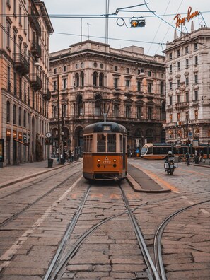 Un tramway circule sur des rails devant un bâtiment historique à l’architecture riche et ornée.